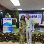 Dustin Rennie accepting membership pin from Donna Regis Prosper 'Sustainable Tourism Conference' and 'Tourism in Full Color.'